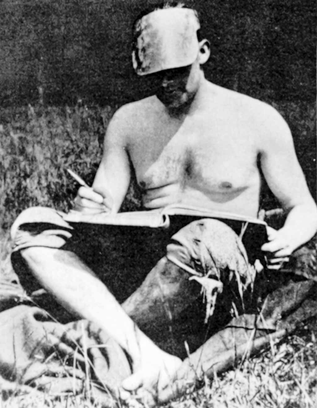 Friedrich&nbsp;Wolf sitz im Gras und schreibt.