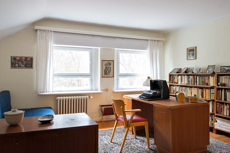 Zimmer mit Schreibtisch, Schreibmaschine, B&uuml;cherregal und Sofa