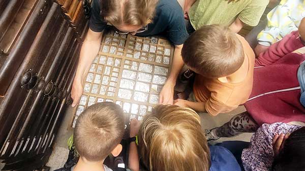 Kinder beugen sich &uuml;ber einen Setzkasten.