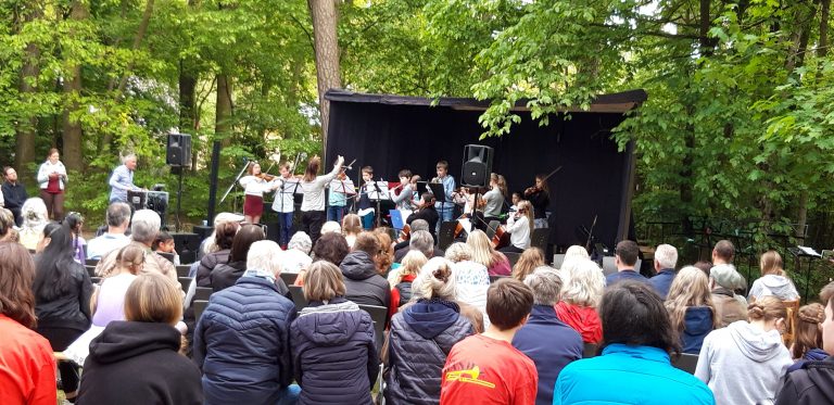 Ein Jugendorchester spielt auf einer Bühne im Garten