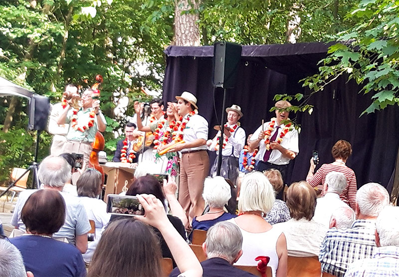 eine Band mit Blumenketten musizieren openair