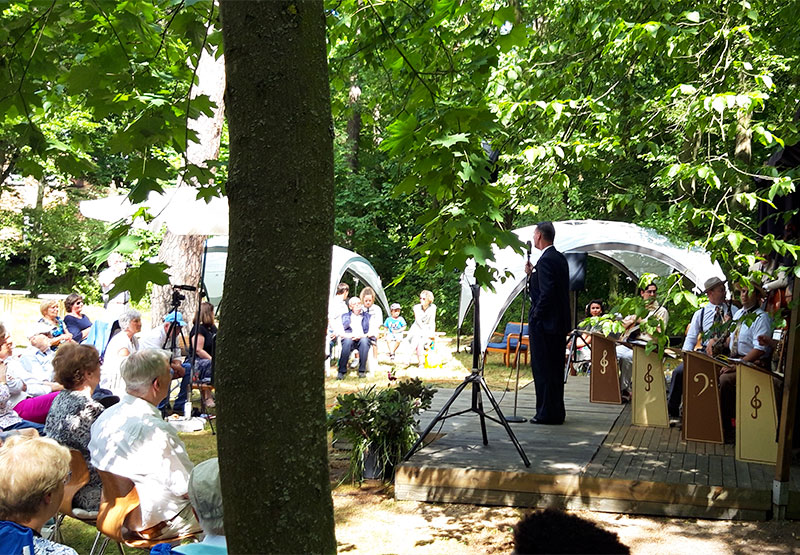 ein Sänger mit Band singt auf einer openair Bühne zum Publikum