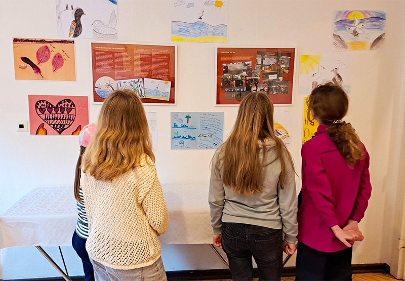 Junge Mädchen schauen sich eine Ausstellung von Kinderzeichnungen an.