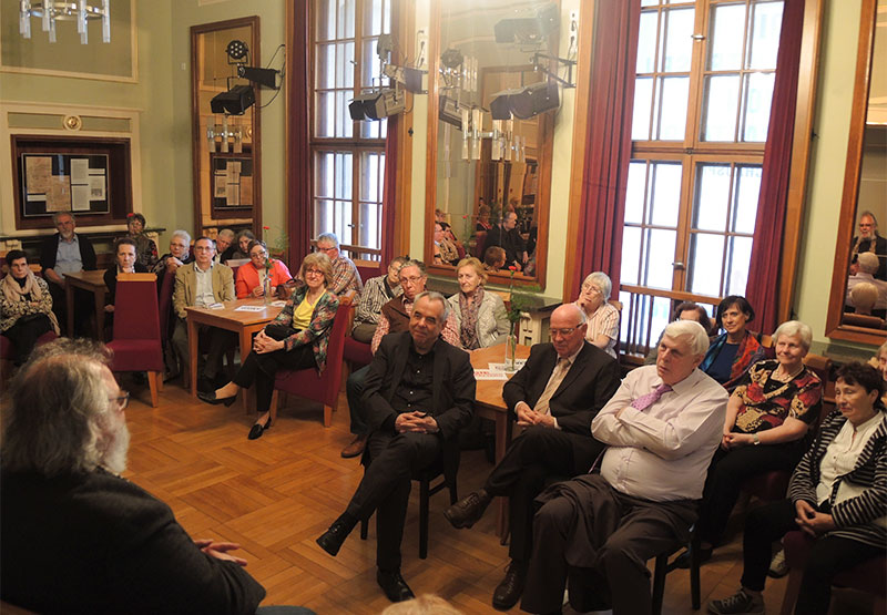 Menschen sitzen im Vorraum des Theater Neustrelitz und unterhalten sich